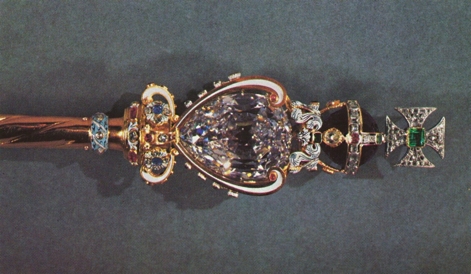 Ein goldenes Königszepter mit Kreuz, besetzt mit Edelsteinen und einem großen Diamanten