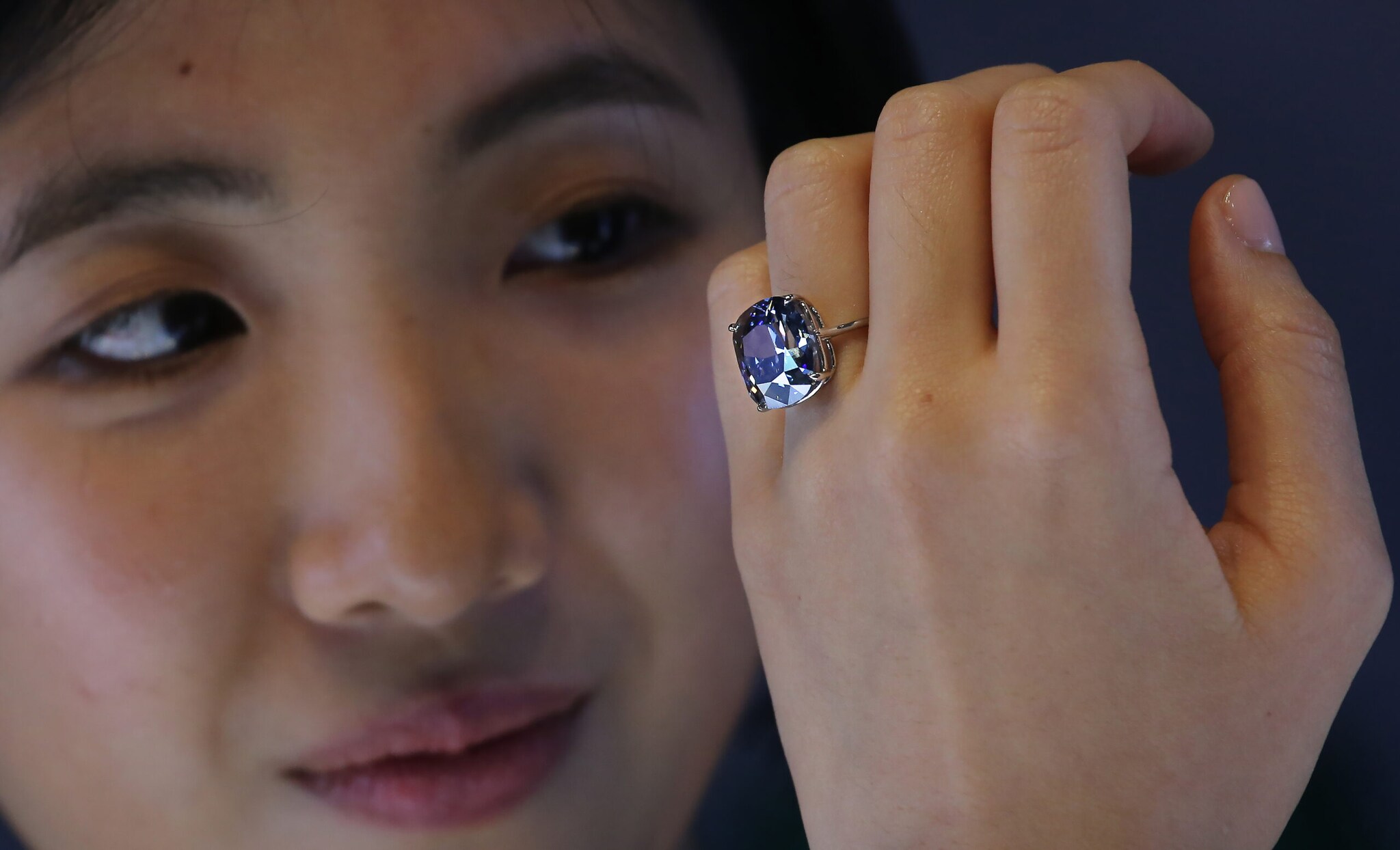 Eine Frau blickt auf einen blauen Diamantring an ihrer Hand