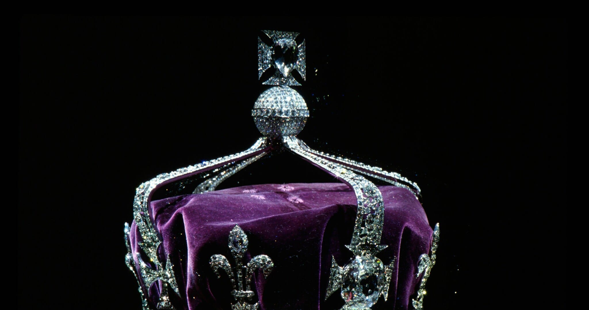 Eine mit Diamanten besetzte, aus Platin gefertigte Krone mit lilafarbenem Samt vor schwarzem Hintergrund Eine mit Diamanten besetzte, aus Platin gefertigte Krone mit lilafarbenem Samt vor schwarzem Hintergrund