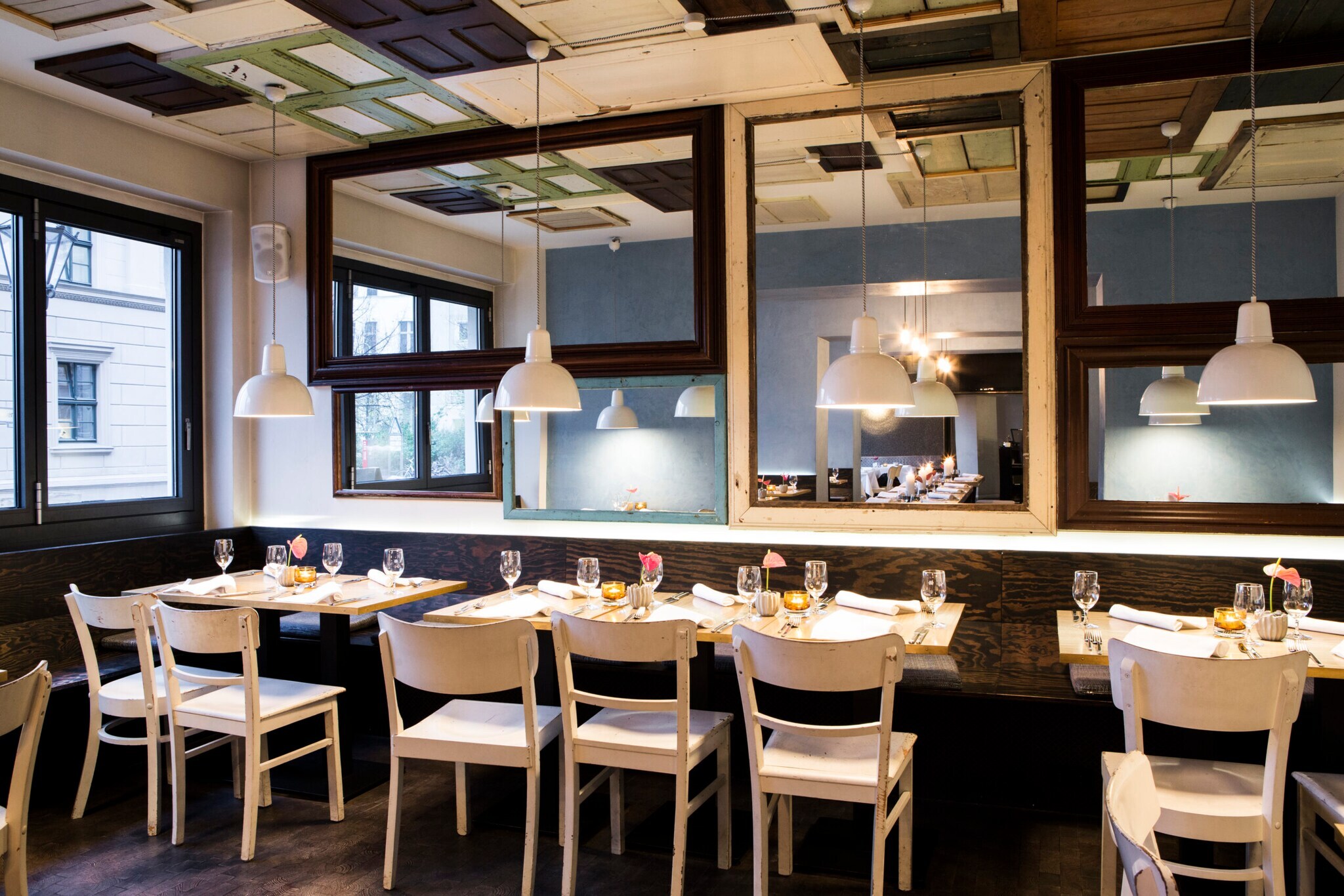 Interieur eines modernen, schicken Restaurants mit gedeckten Tischen und Spiegelwand