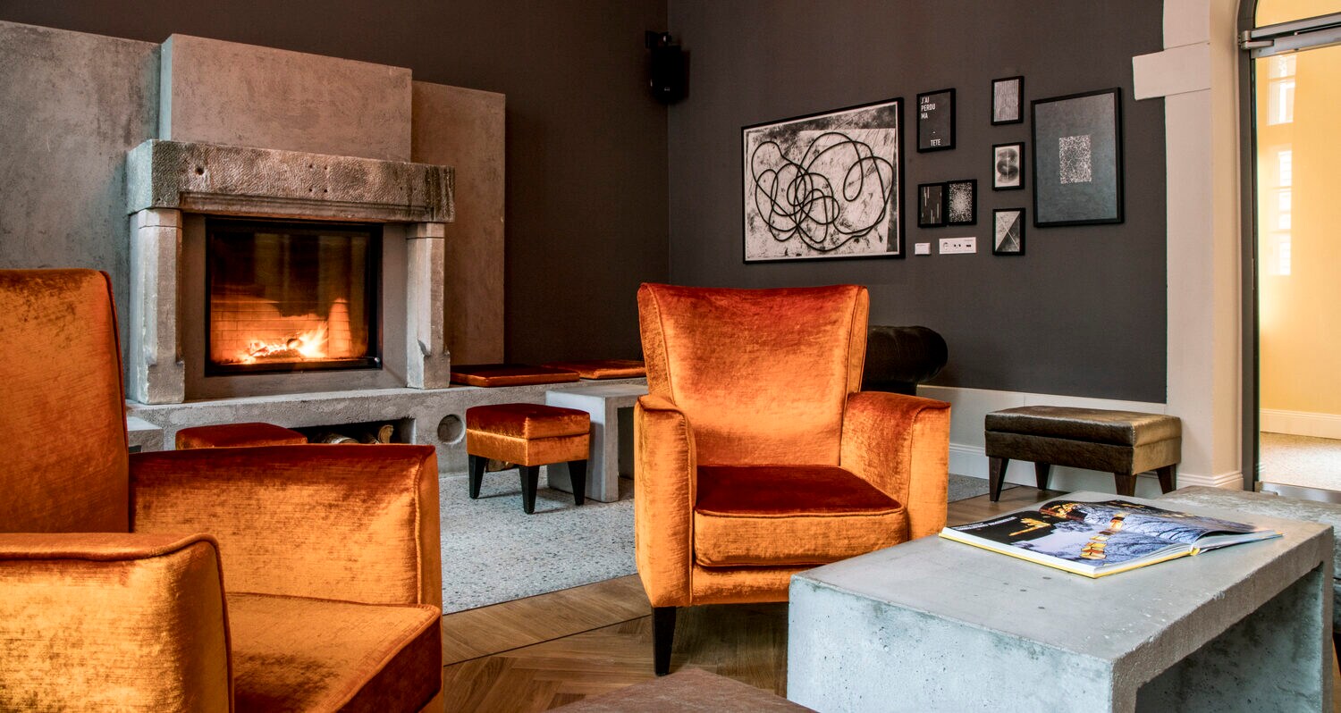 Innenansicht eines Zimmers mit dunkler Tapete, Kamin und Sesseln