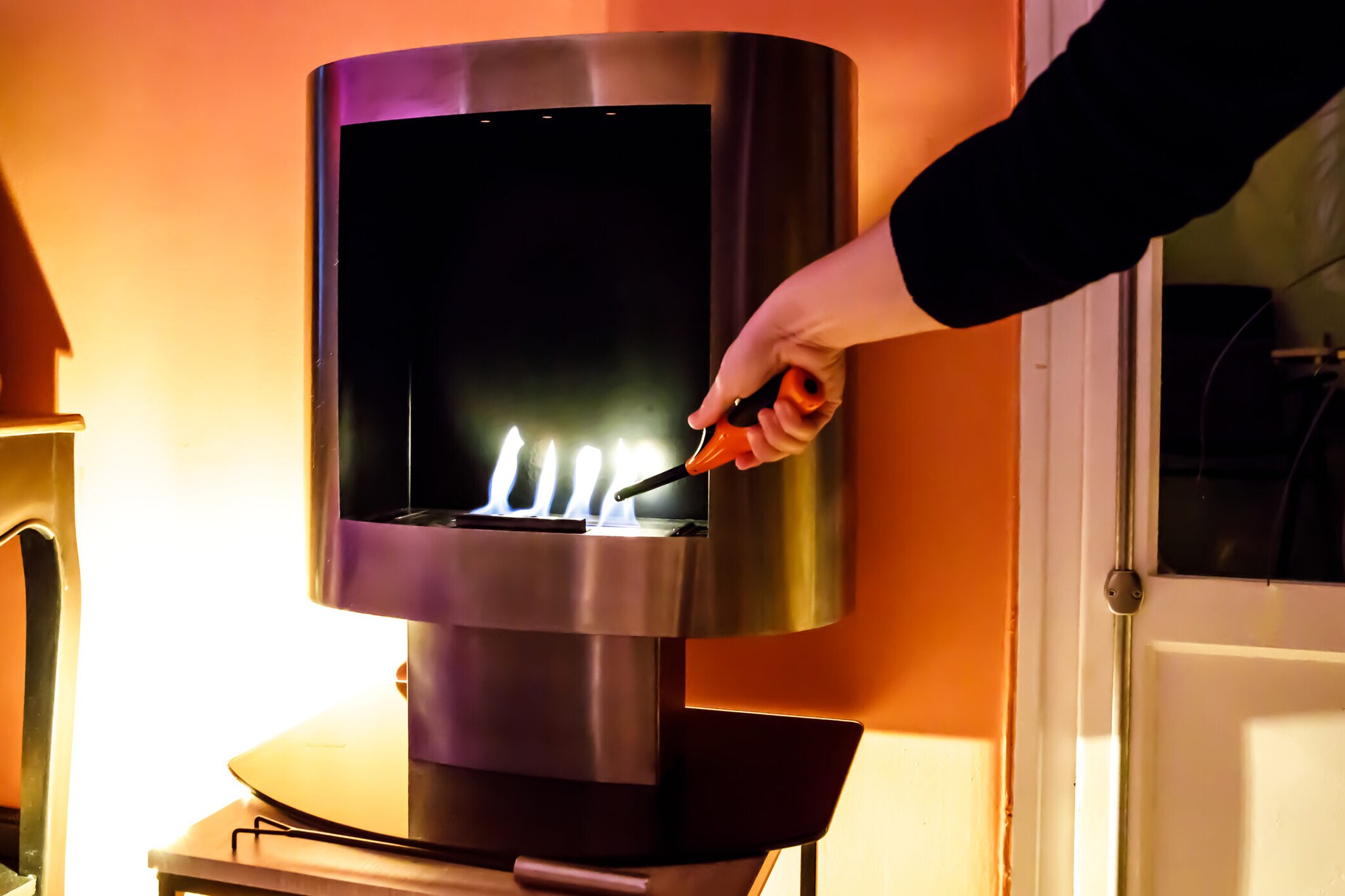 Mit einem Stabfeuerzeug wird ein Ethanolkamin entzündet