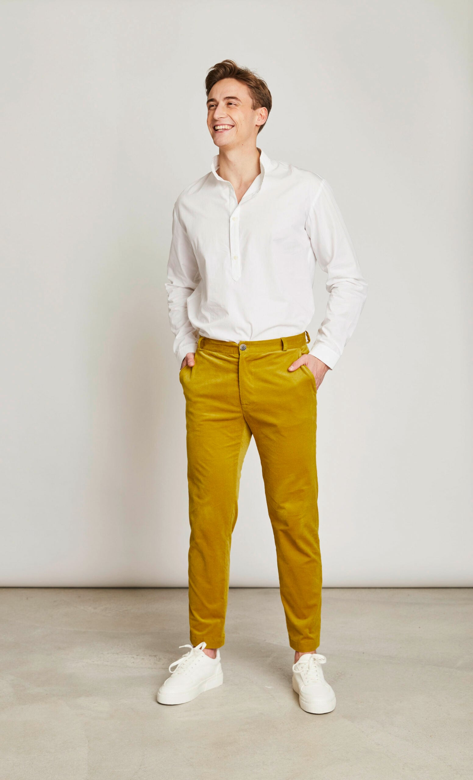 Ein junger Mann in weißem Hemd und senffarbener Stoffhose Ein junger Mann in weißem Hemd und senffarbener Stoffhose