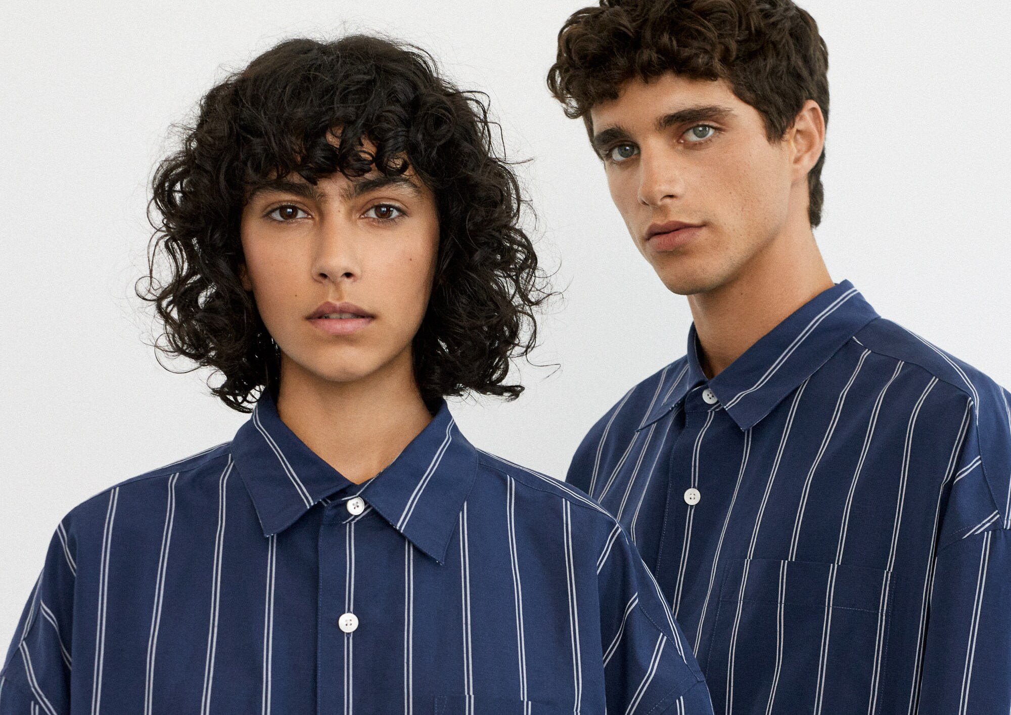 Close-up einer jungen Frau und eines jungen Mannes in einem blauen Unisex-Hemd mit weißen Streifen