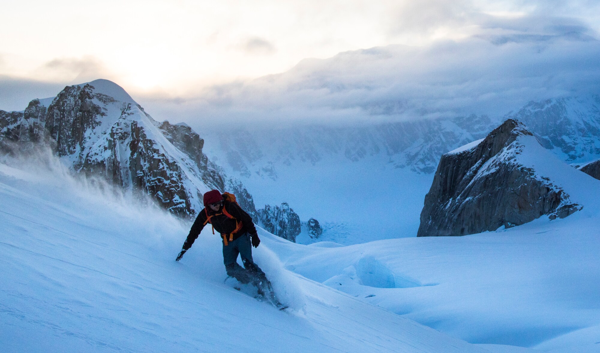 Ein Snowboarder fährt durch den Tiefschnee im Gebirge, im Hintergrund Gipfelpanorama in den Wolken Ein Snowboarder fährt durch den Tiefschnee im Gebirge, im Hintergrund Gipfelpanorama in den Wolken