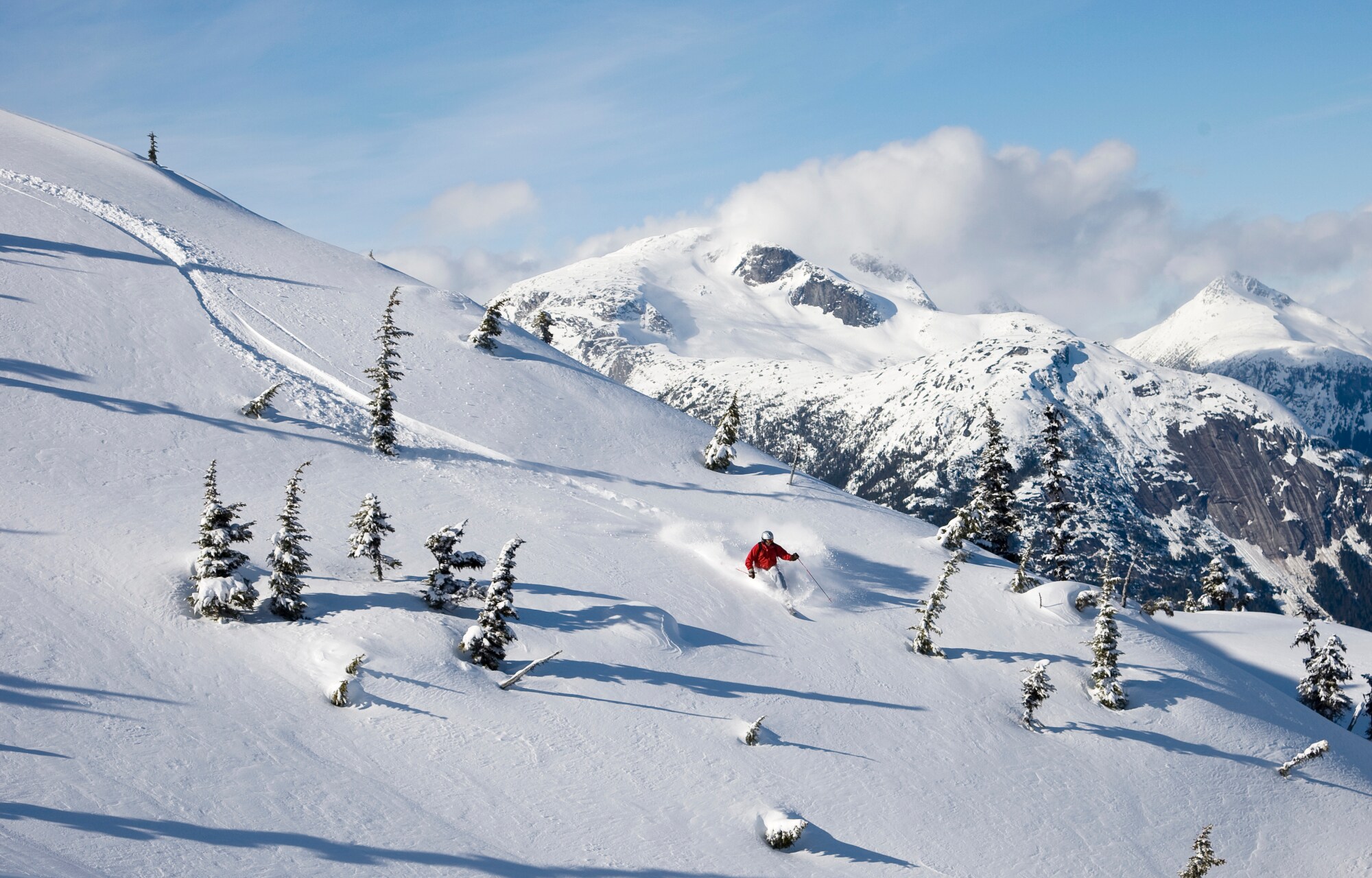 Ein Skifahrer fährt durch den Tiefschnee in den Bergen Ein Skifahrer fährt durch den Tiefschnee in den Bergen