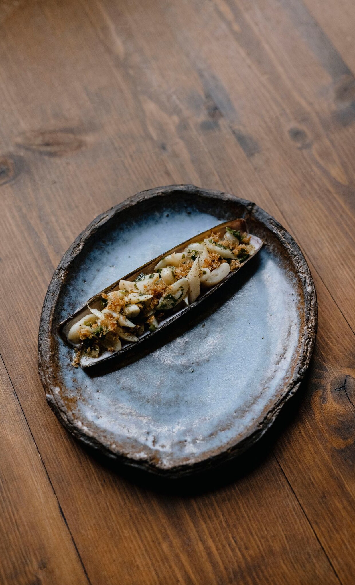 Eine essfertig zubereitete Schwertmuschel auf einem Keramikteller Eine essfertig zubereitete Schwertmuschel auf einem Keramikteller