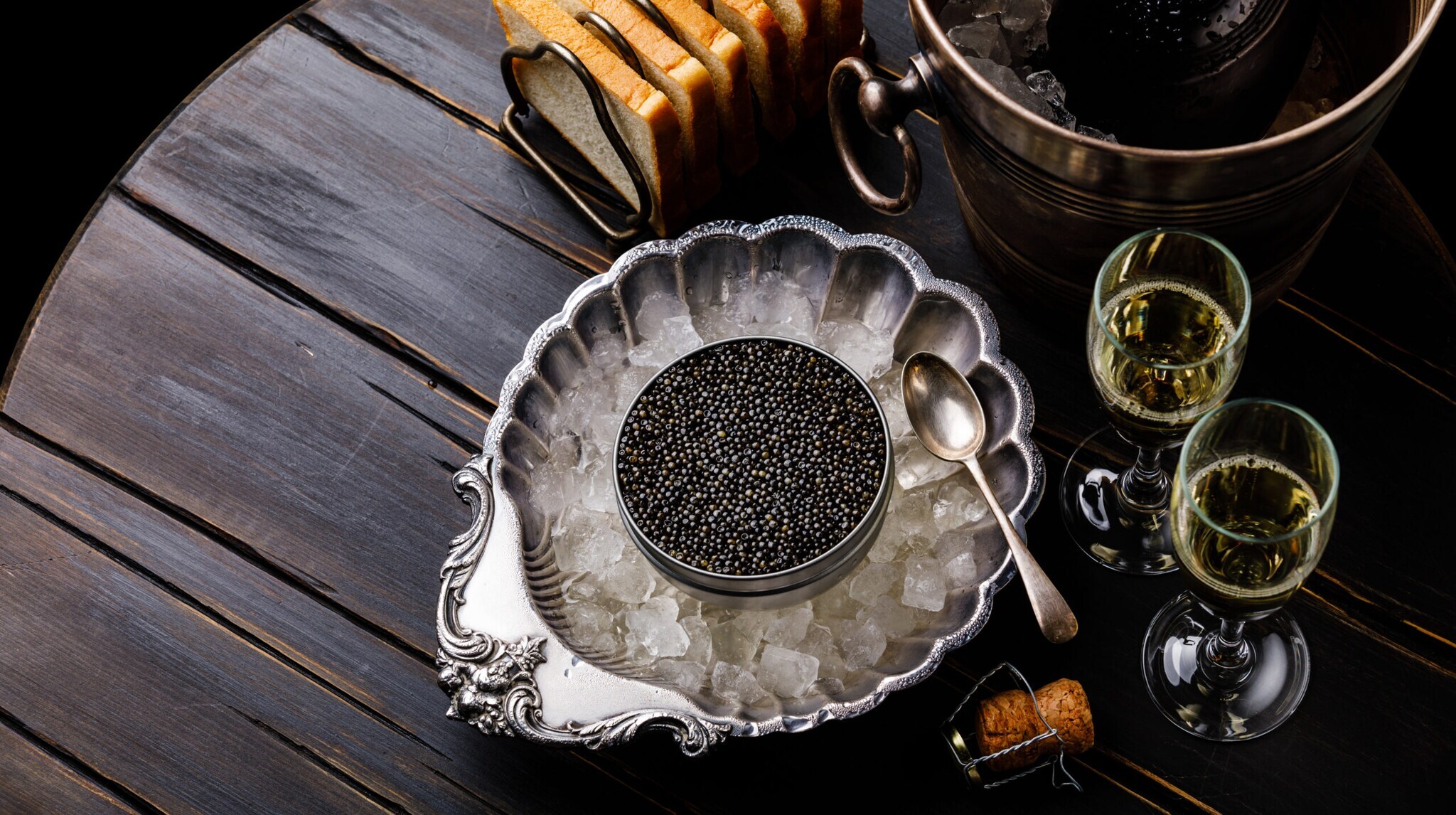 Kaviar in Silberschale auf Eis angerichtet, daneben Sektgläser und Toastbrot