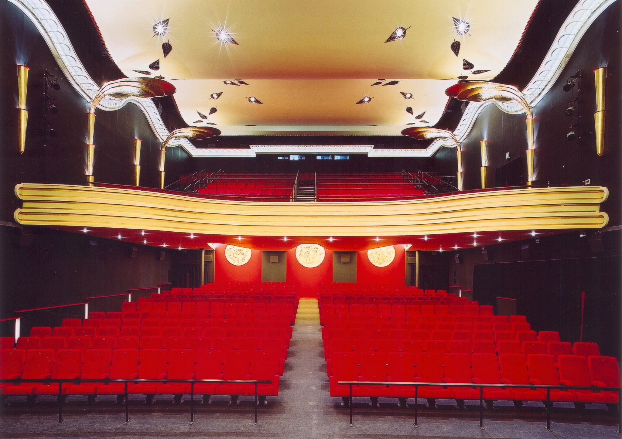 Beleuchteter Kinosaal mit roten Stühlen und schwarzen Wänden Beleuchteter Kinosaal mit roten Stühlen und schwarzen Wänden