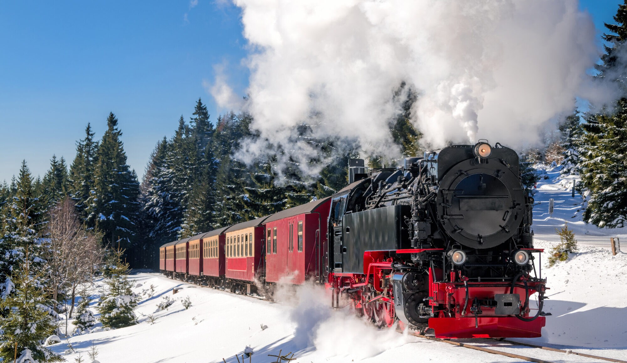Historischer Dampfzug fährt durch eine verschneite Landschaft Historischer Dampfzug fährt durch eine verschneite Landschaft