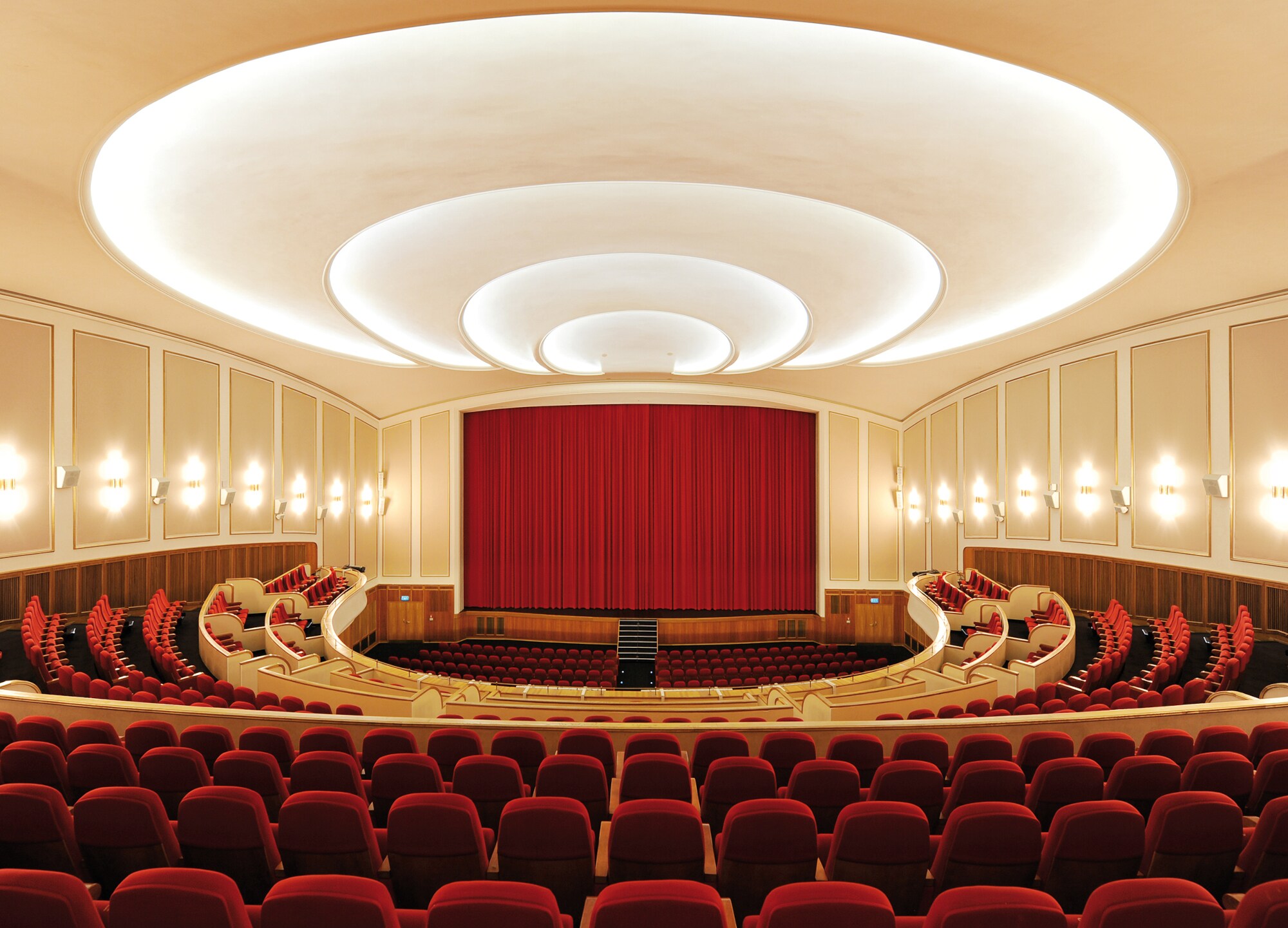 Großer Kinosaal mit Bühne und roten Stühlen