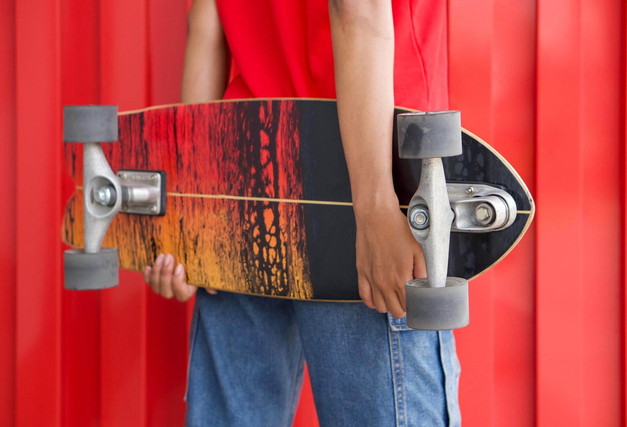 Rückansicht einer Frau, die ein Longboard hinter dem Rücken hält