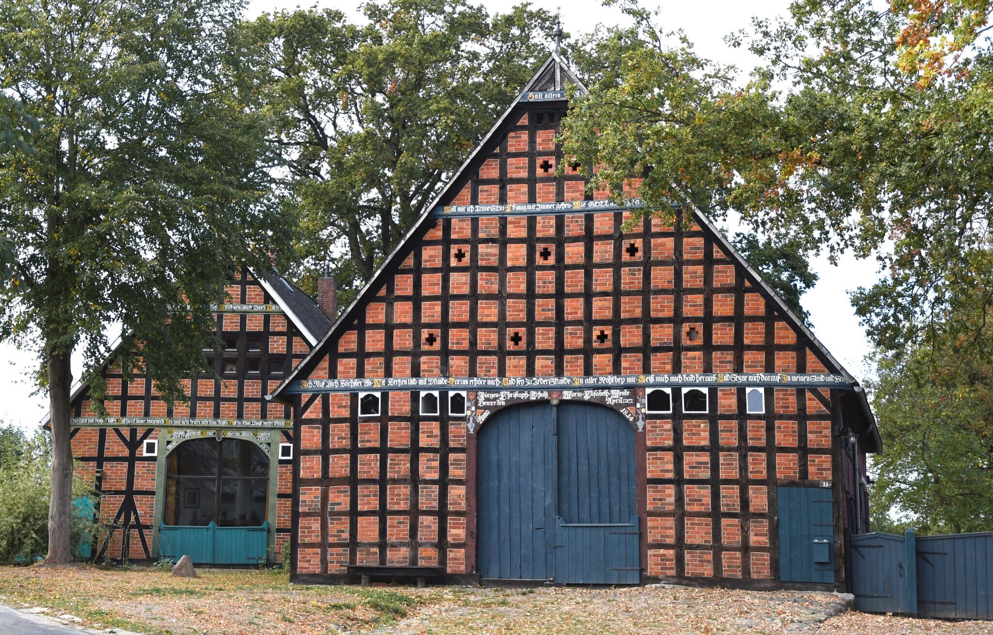 Zwei Fachwerkhäuser mit blauen Toren, daneben Bäume