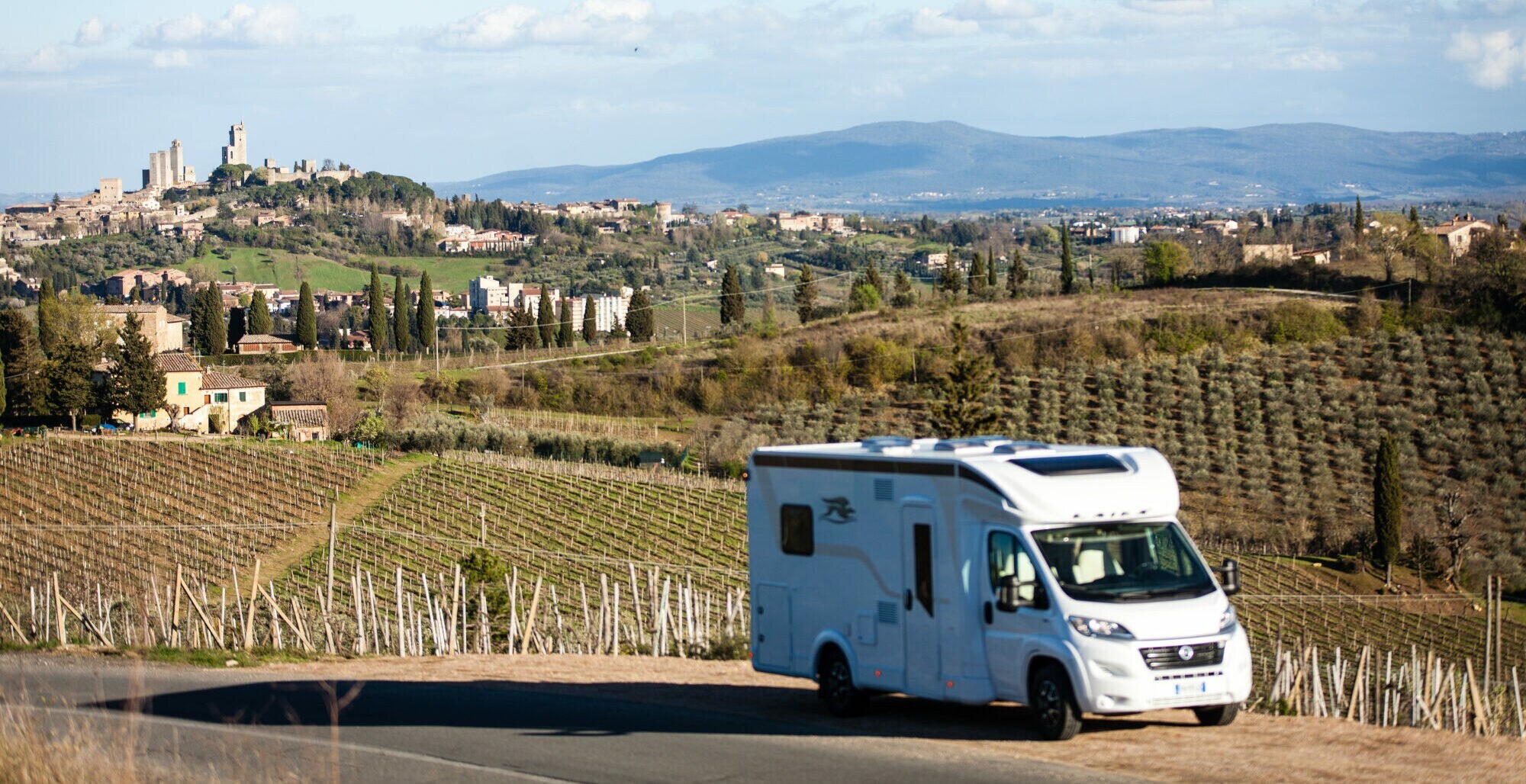 Ein Wohnmobil steht auf einer Straße vor der Skyline von San Gimignano
