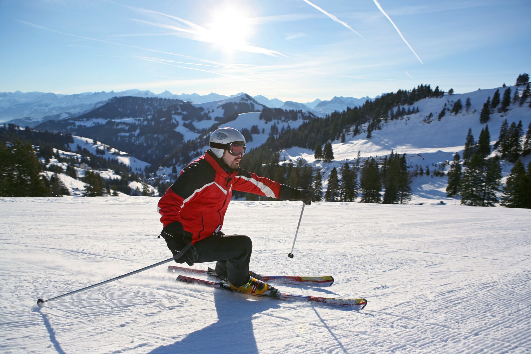 Ein Mann auf Skiern fährt einen verschneiten Berg hinunter.