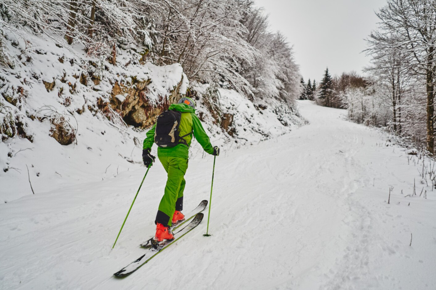 Eine Person in grüner Kleidung beim Skitourengehen