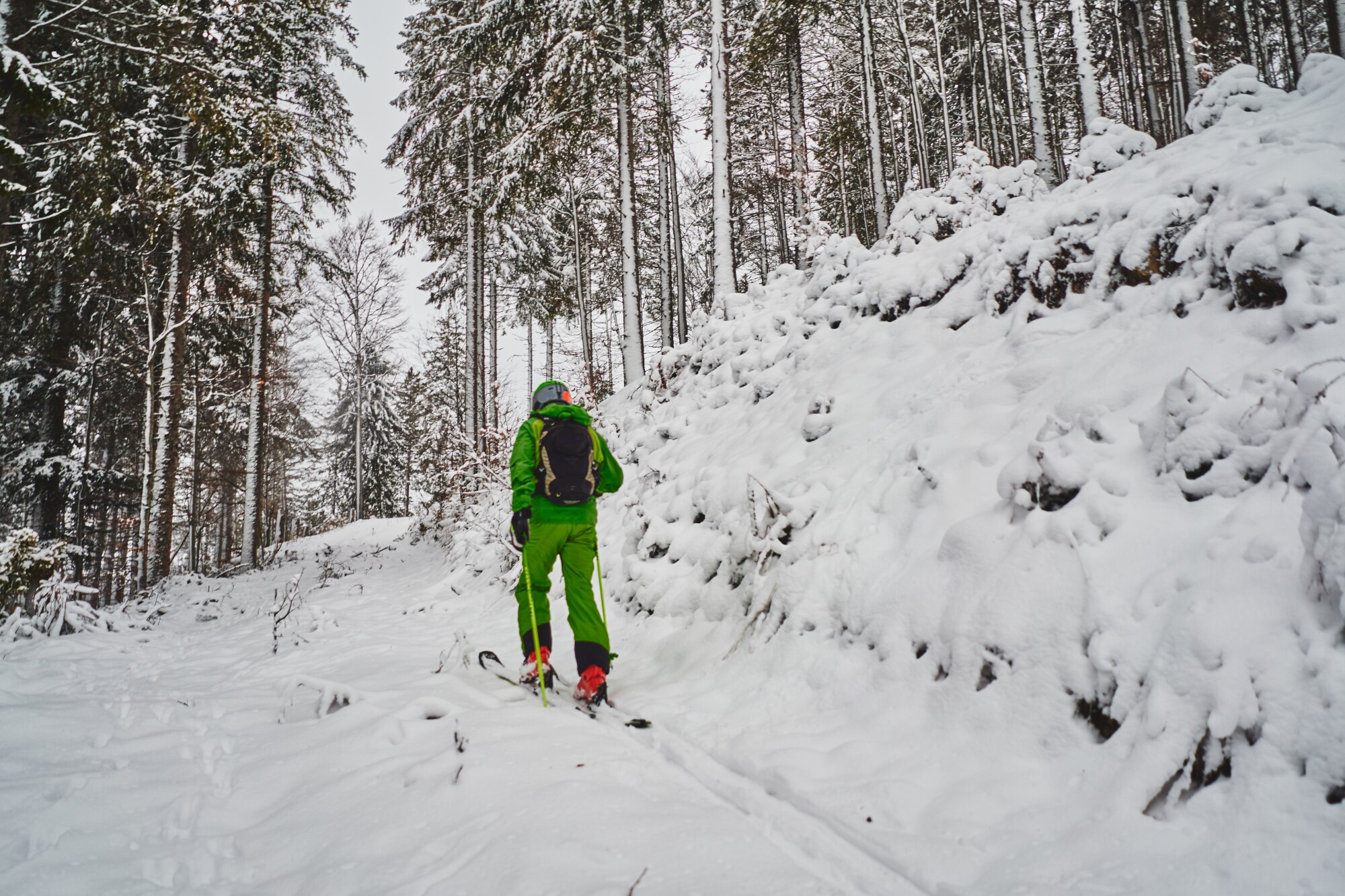 Ein Tourengeher in einem schneebedeckten Bergwald