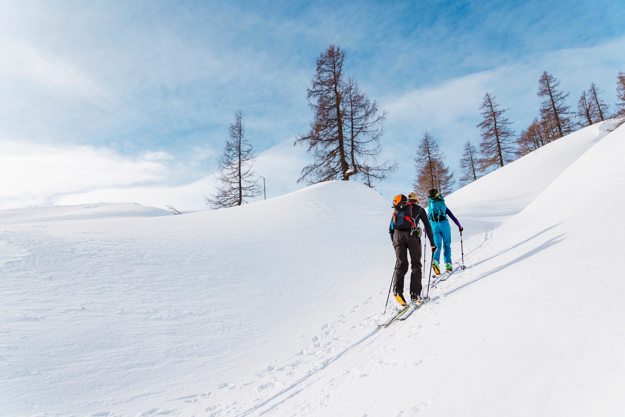 Zwei Menschen mit Skiausrüstung wandern auf Ski einen Schneeberg hoch