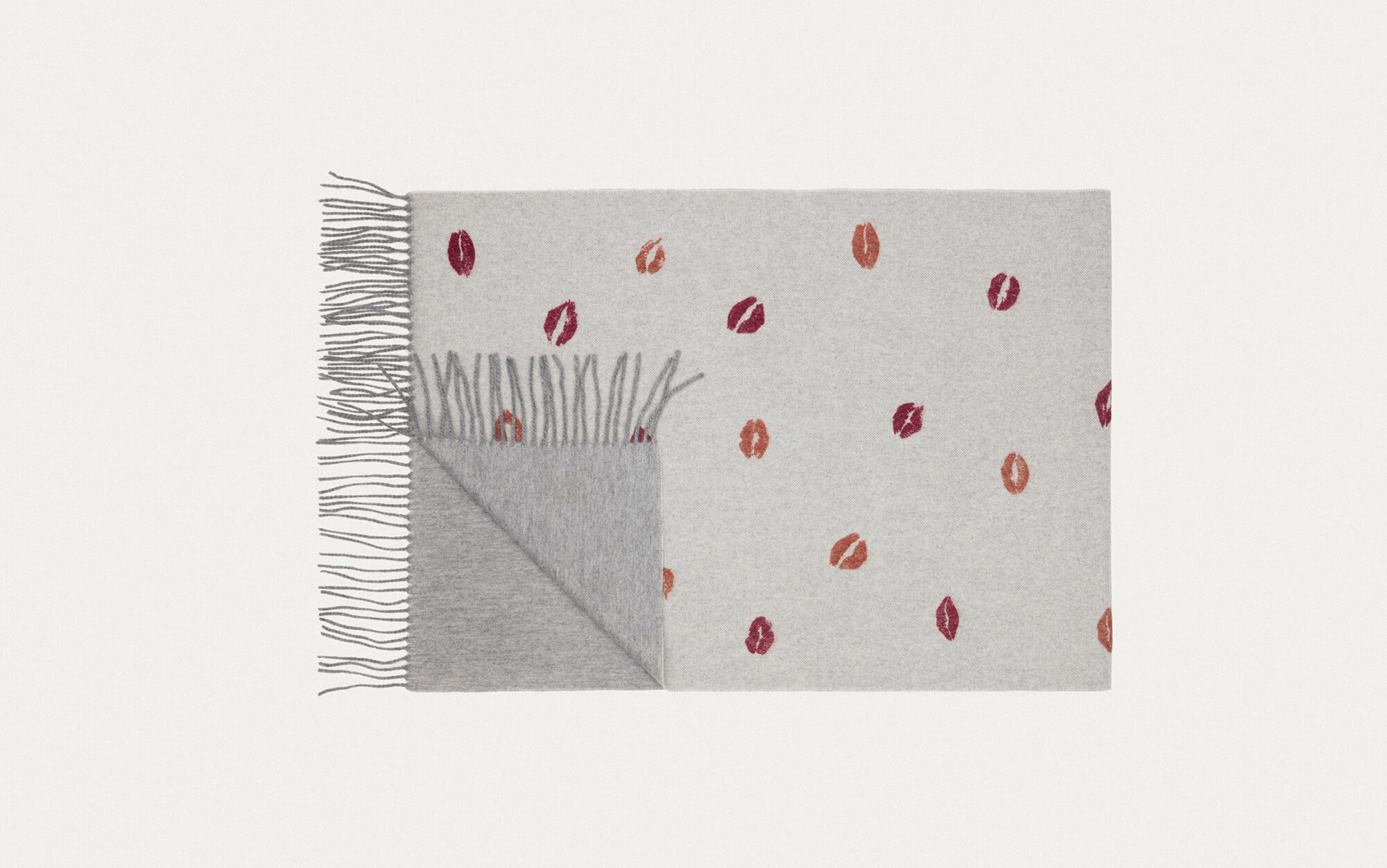 Ein grauer Schal mit Fransen und Kussmotiven