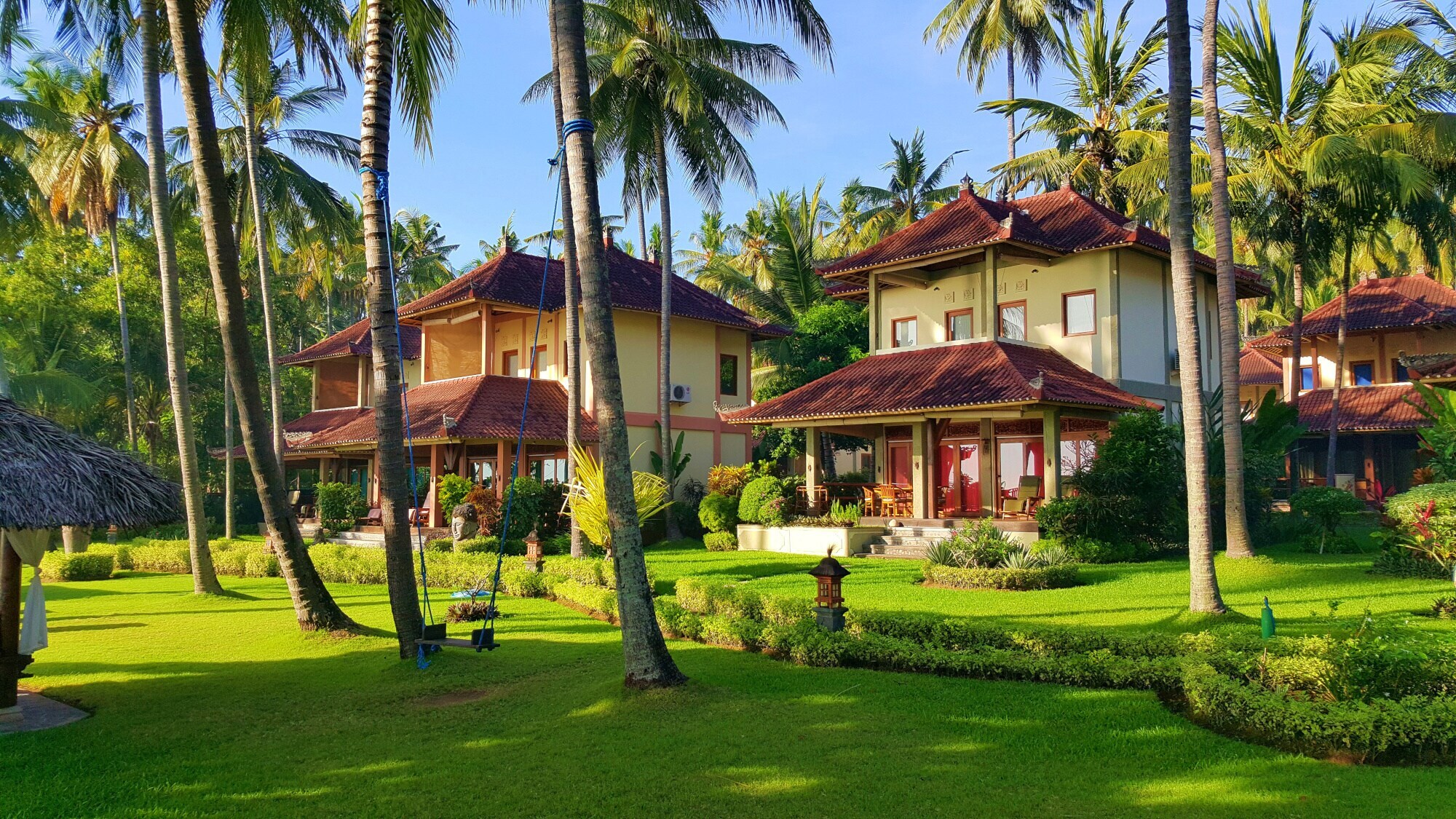 Drei Häuser stehen zwischen Kokospalmen