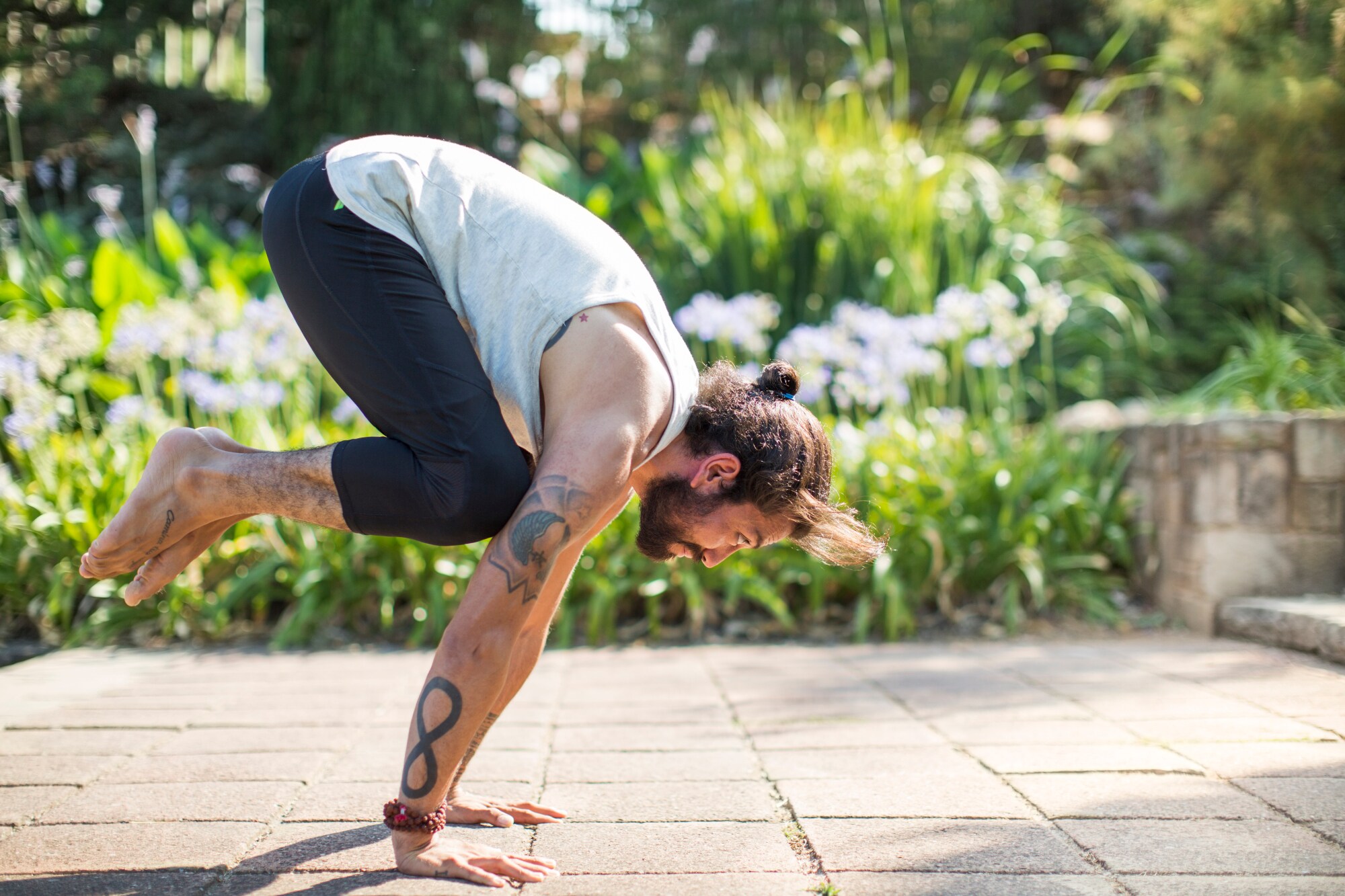Ein sportlicher Mann macht eine Yogaübung im Grünen