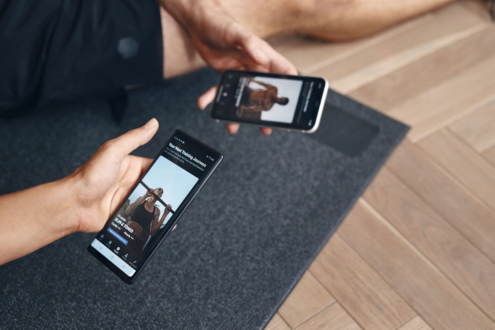 Zwei Hände halten jeweils ein Smartphone mit Fitness-Inhalten. Zwei Hände halten jeweils ein Smartphone mit Fitness-Inhalten.