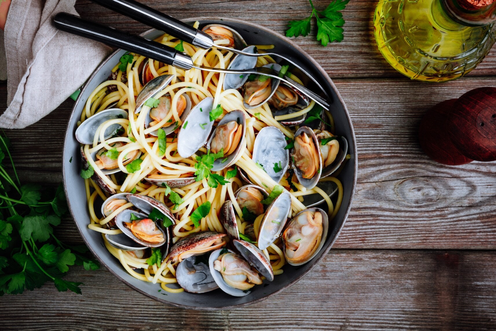 Spaghetti alle vongole im Teller angerichtet auf einer Holztafel Spaghetti alle vongole im Teller angerichtet auf einer Holztafel