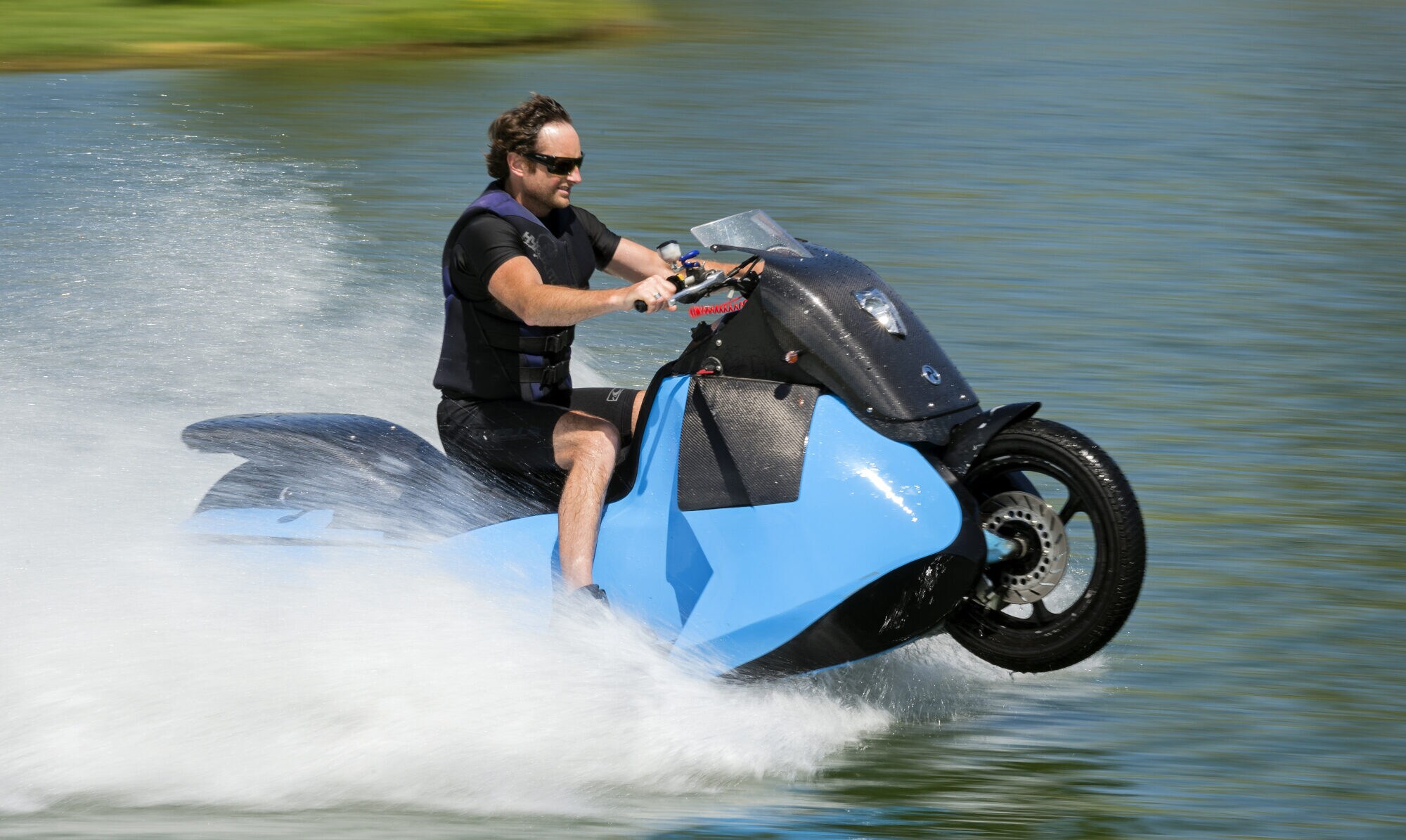 Ein Mann fährt mit einem Amphibienfahrzeug (halb Motorrad, halb Jetski) auf dem Wasser