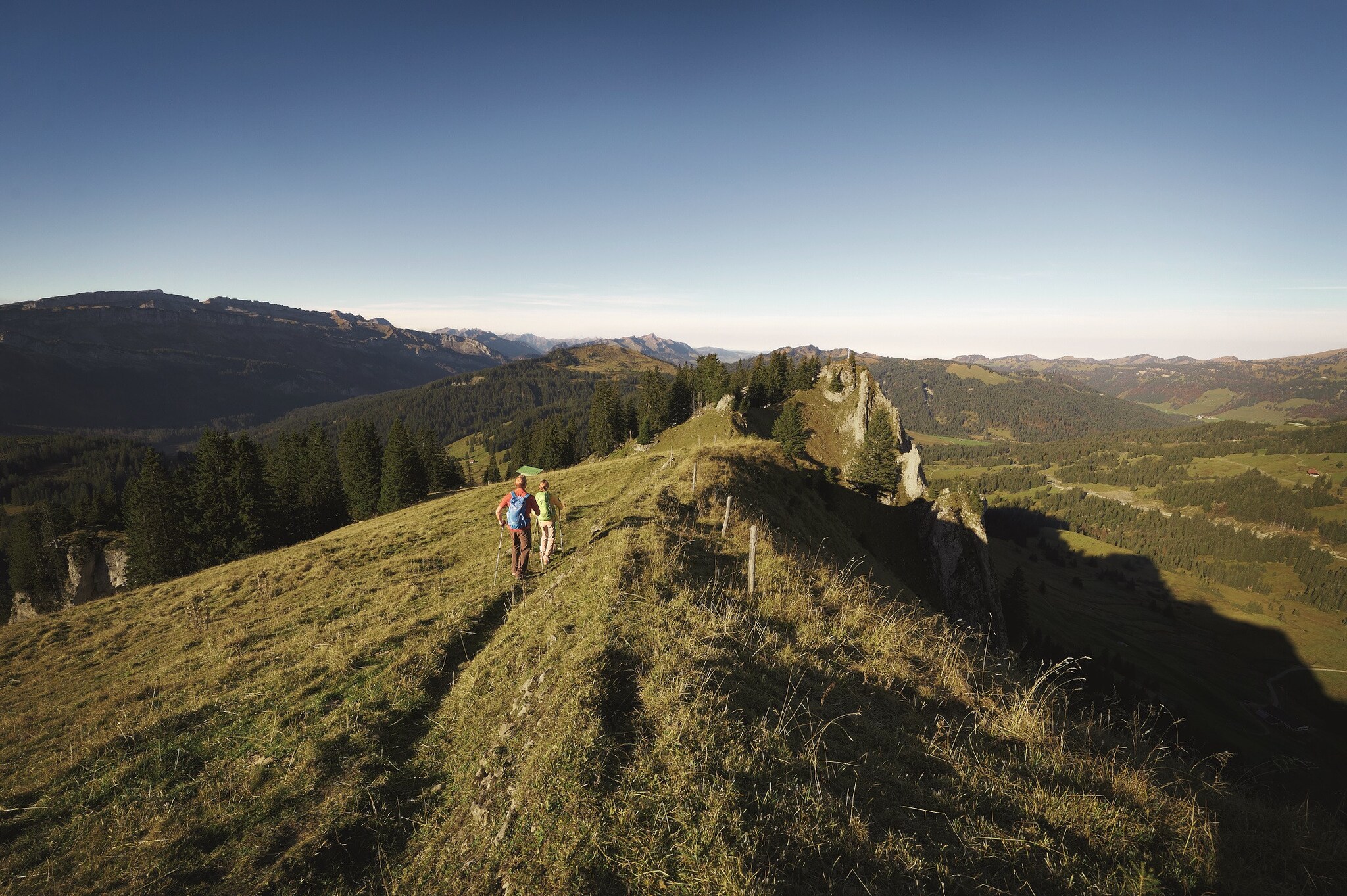 Zwei wandernde Personen auf einem Gipfelgrat, rundherum Berge Zwei wandernde Personen auf einem Gipfelgrat, rundherum Berge