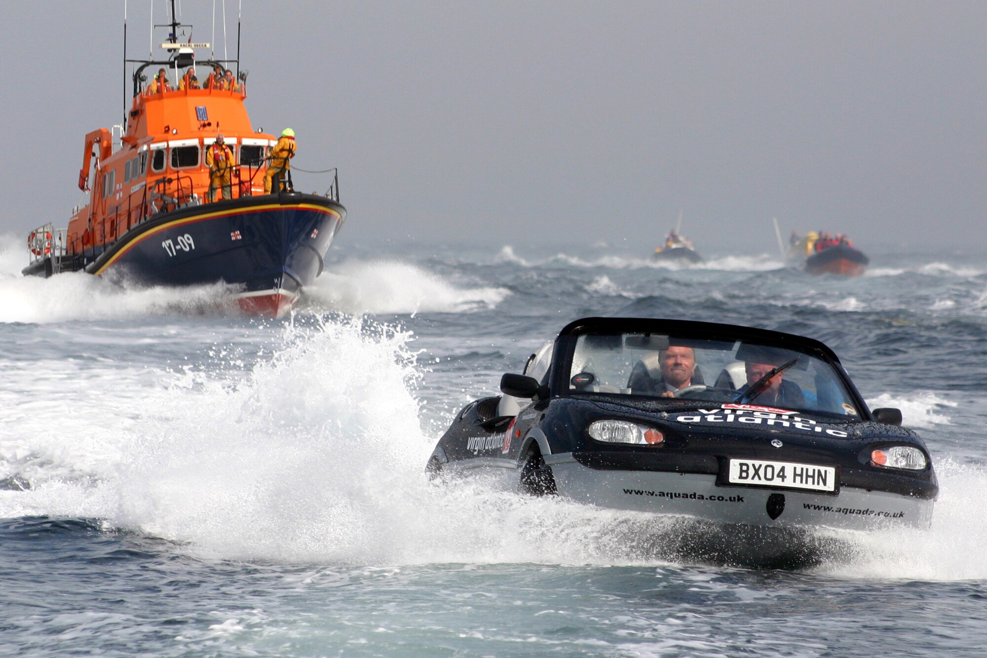 Ein Amphibienfahrzeug fährt auf dem Wasser zwischen mehreren Schiffen