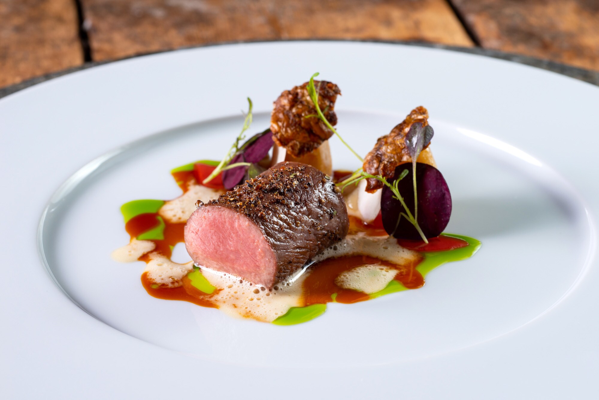 Ein Stück Fleisch mit Garnierung und Soße auf einem weißen Teller