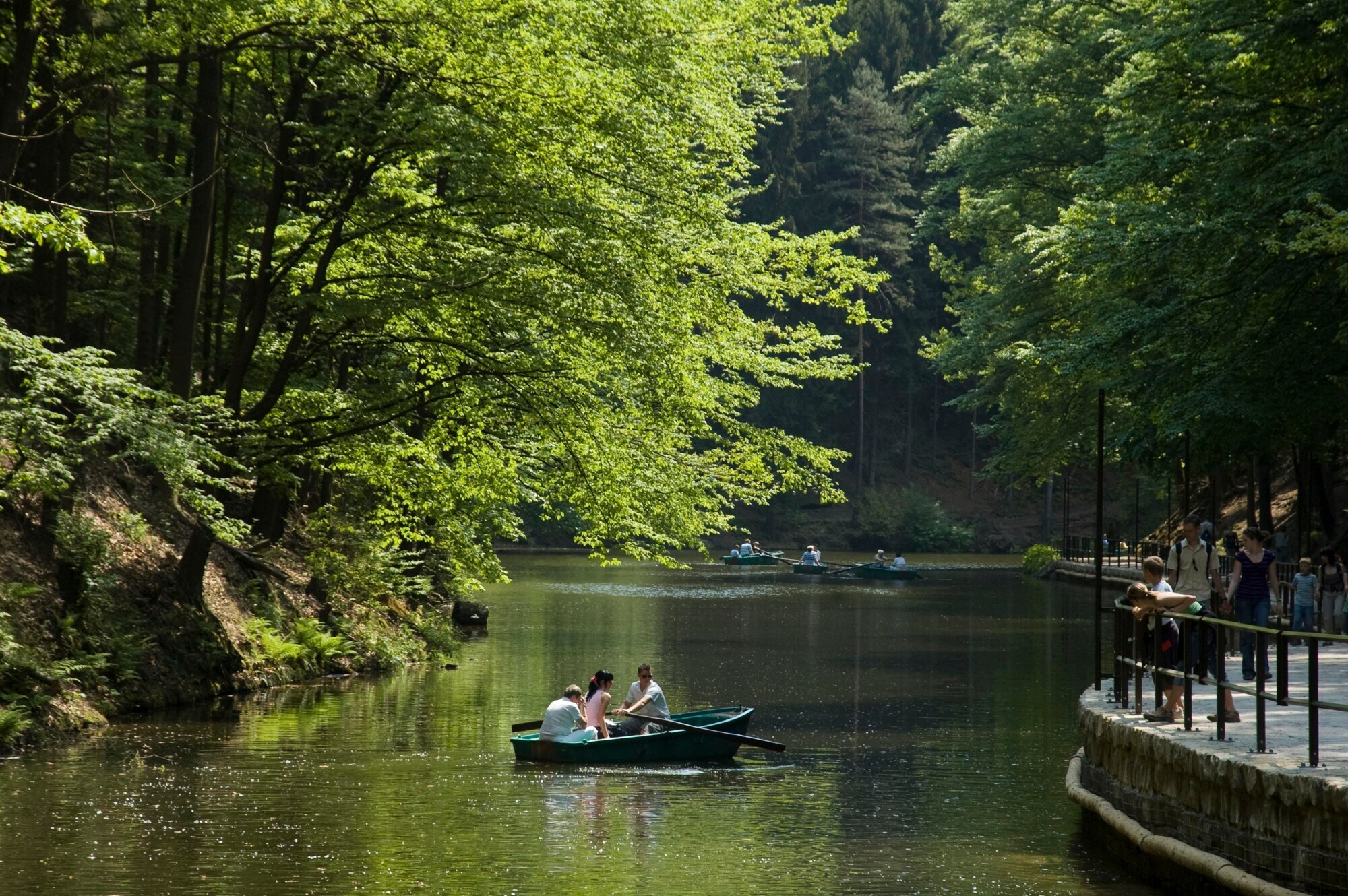 Ein idyllischer See mit Ruderbooten und Spaziergängern am Ufer Ein idyllischer See mit Ruderbooten und Spaziergängern am Ufer