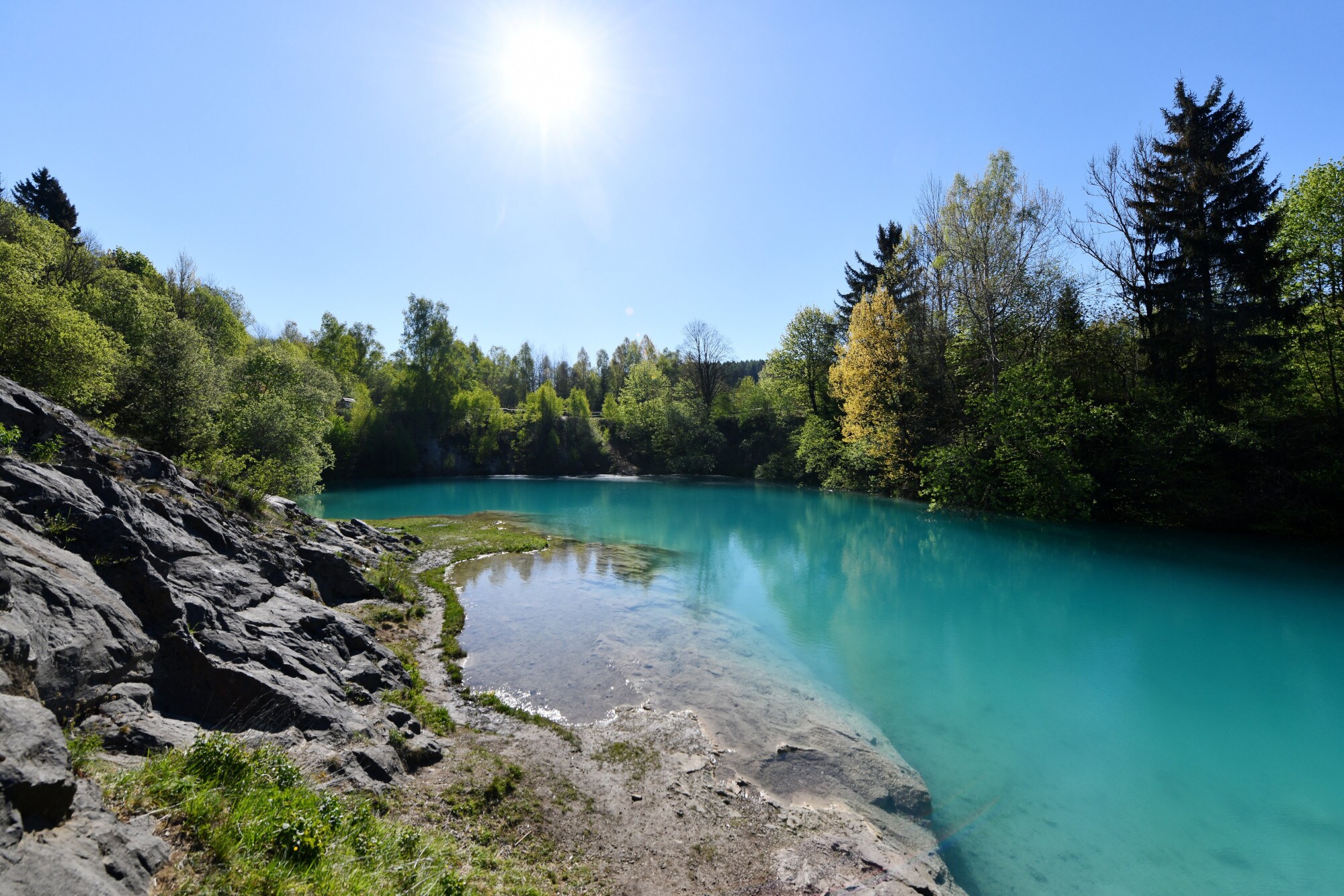 Ein kleiner, türkisblauer See, umrahmt von Bäumen Ein kleiner, türkisblauer See, umrahmt von Bäumen