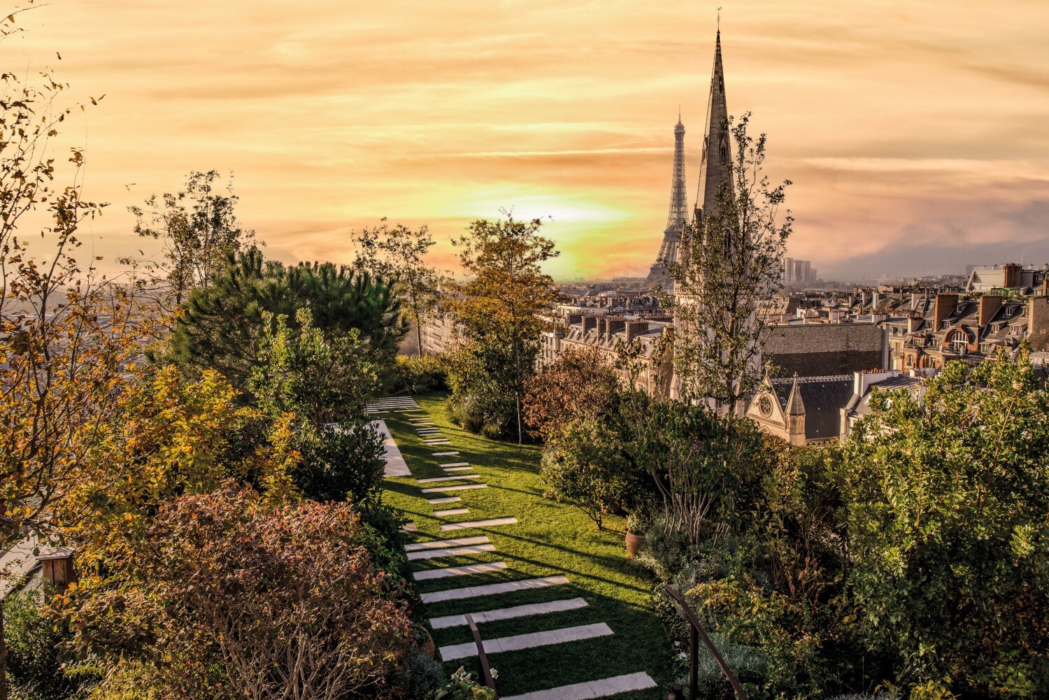 Eine Dachterrasse mit Bäumen, im Hintergrund Häuser und der Eiffelturm