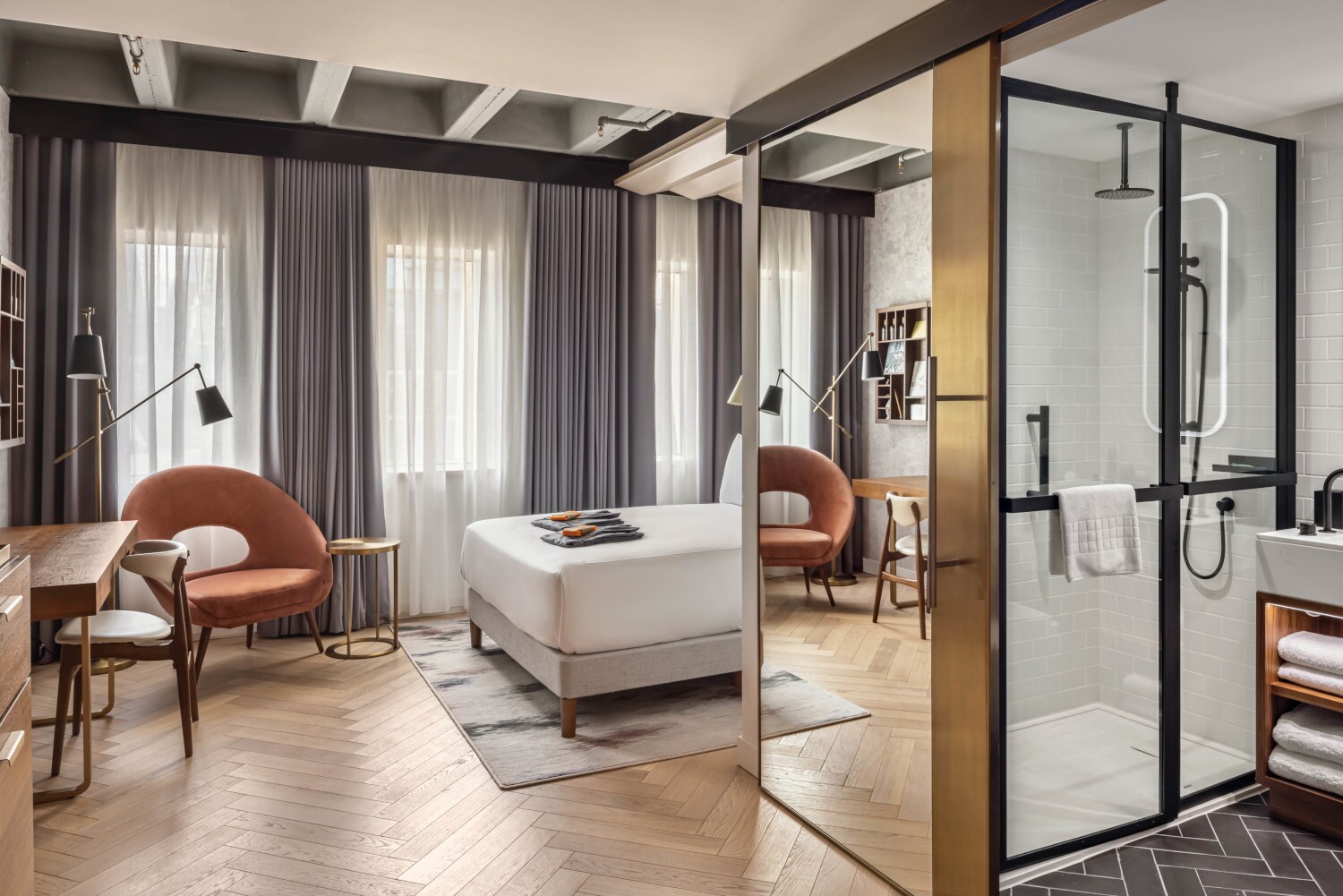 Hotelzimmer in warmen Farben mit Bett, Stuhl, Tisch und geöffneter Badezimmertür