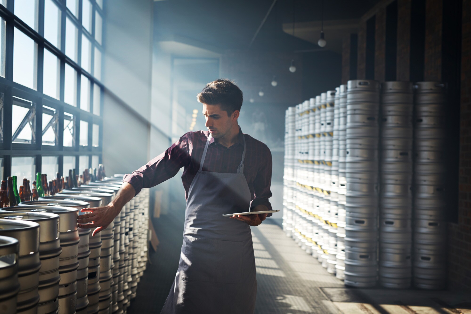 Ein Prüfer in einer Halle mit Bierfässern