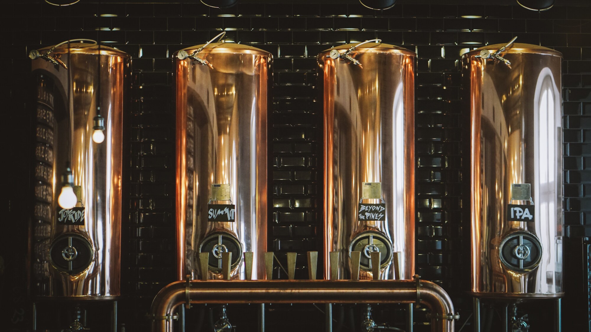 Vier kupferne Bierkessel, im Vordergrund eine Bierzapfsäule