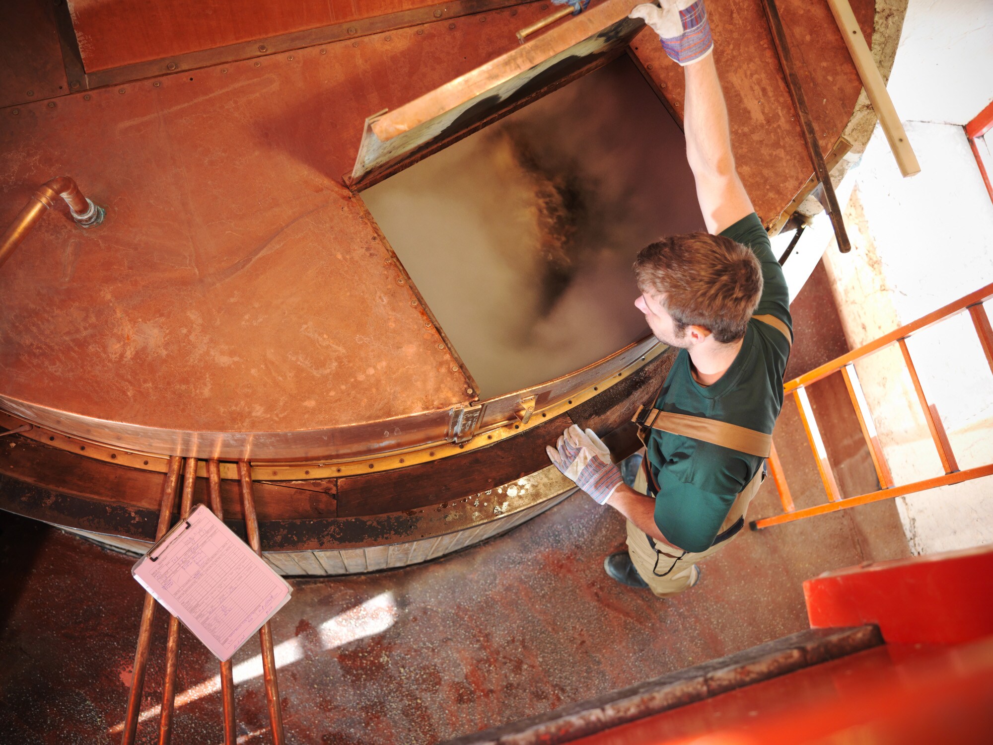 Der Blick von oben in einen geöffneten Sudkessel einer Brauerei, in dem Würze und Hopfen kochen Der Blick von oben in einen geöffneten Sudkessel einer Brauerei, in dem Würze und Hopfen kochen