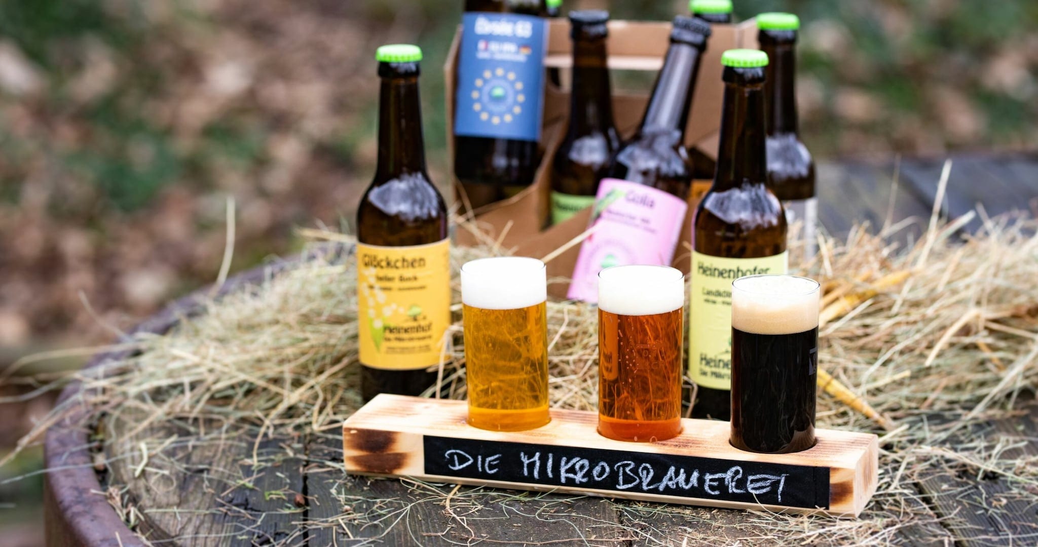 Bierflaschen und drei Sorten Bier sind auf einem Holzfass arrangiert Bierflaschen und drei Sorten Bier sind auf einem Holzfass arrangiert