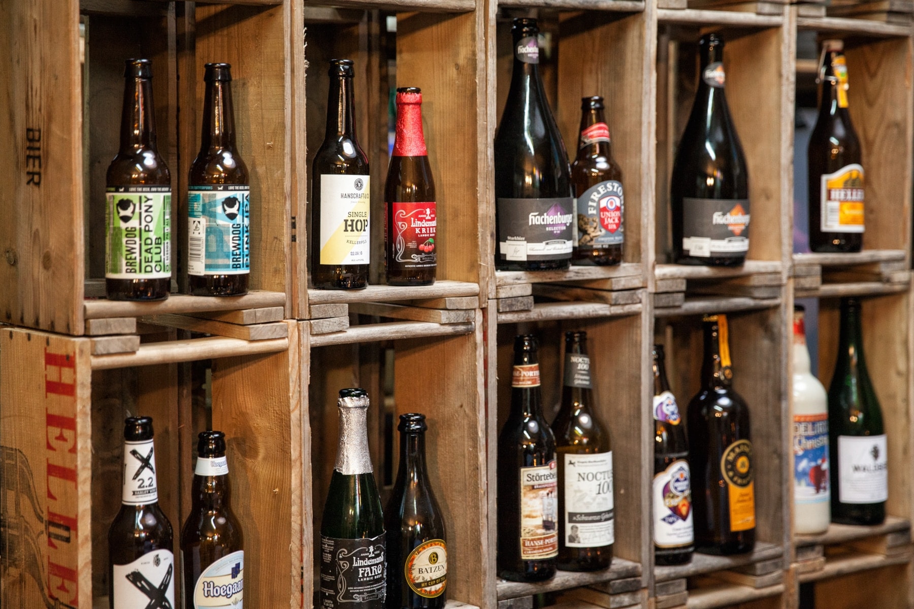 In einem Holzregal stehen verschiedene Bierflaschen In einem Holzregal stehen verschiedene Bierflaschen