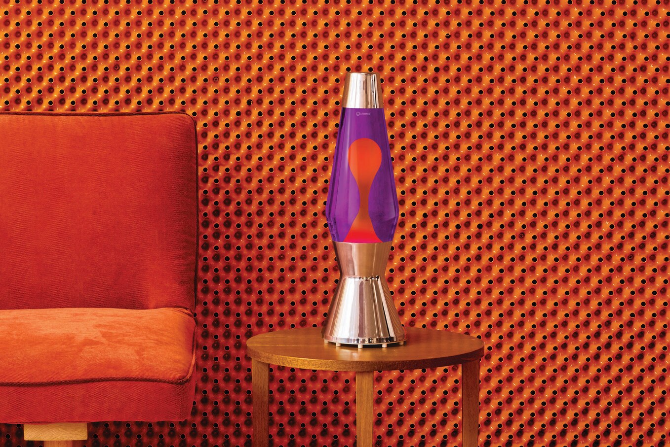 Eine Lavalampe steht auf einem Holztisch vor orangefarbener Wand. Eine Lavalampe steht auf einem Holztisch vor orangefarbener Wand.