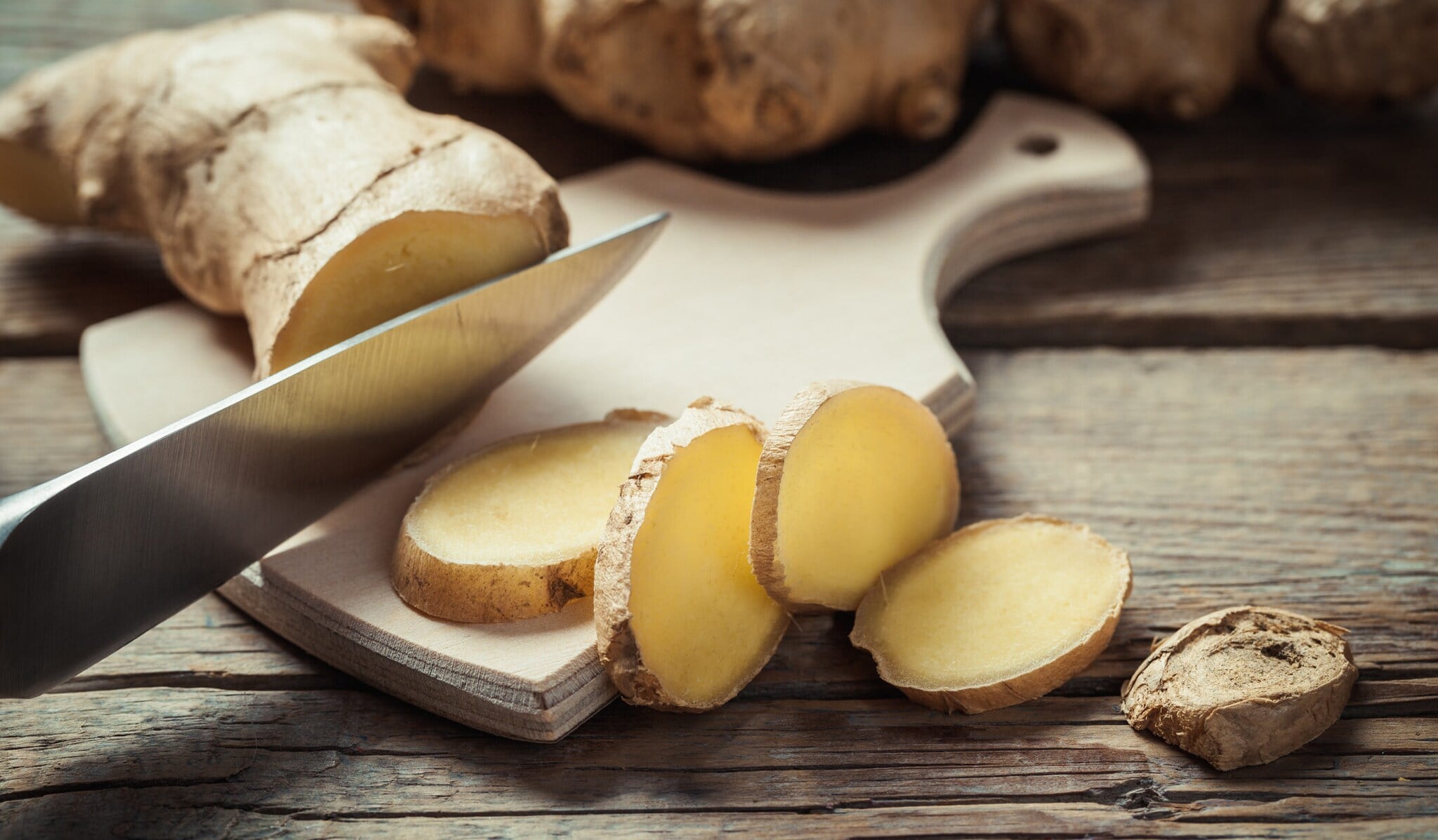 Eine geschnittene Ingwer-Wurzel liegt auf einem Schneidebrett auf rustikalen Tisch Eine geschnittene Ingwer-Wurzel liegt auf einem Schneidebrett auf rustikalen Tisch
