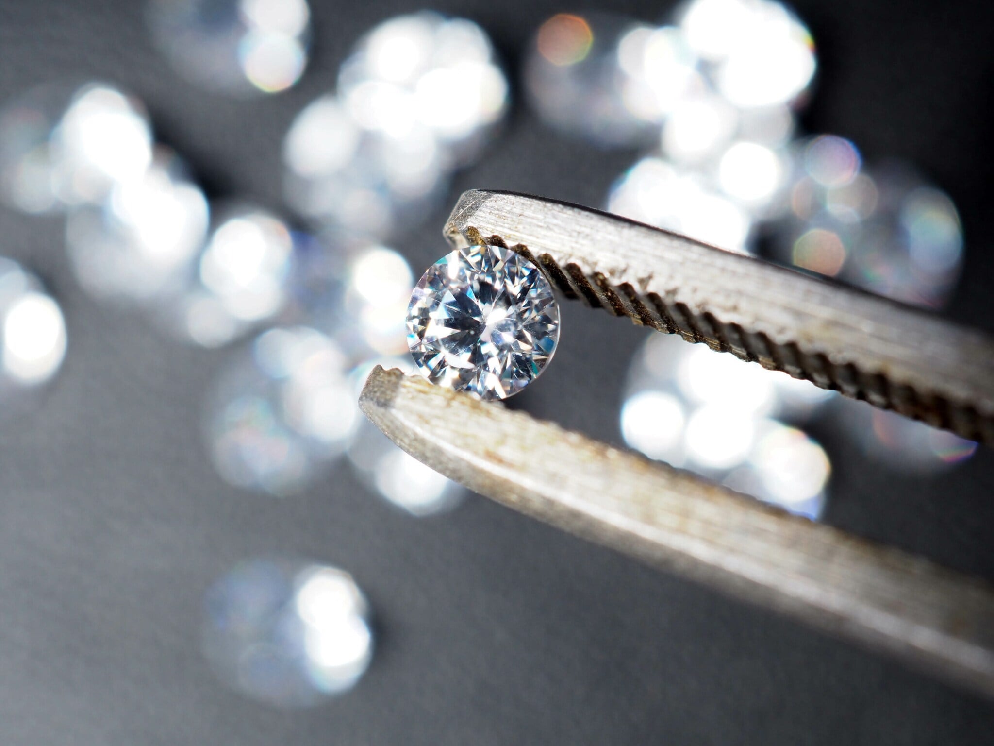 Ein runder Diamant wird von einer Pinzette gehalten Ein runder Diamant wird von einer Pinzette gehalten