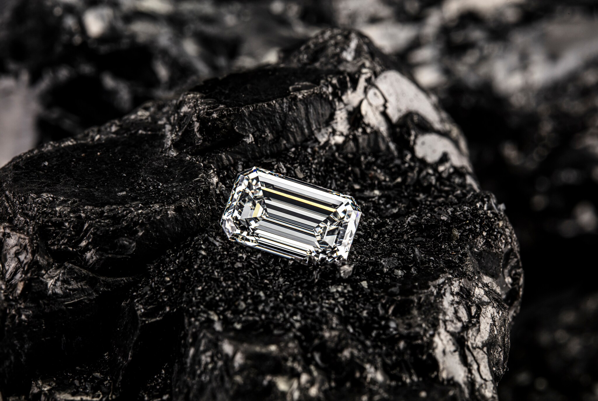 Einzelner Smaragddiamant auf schwarzem Kohlehintergrund.