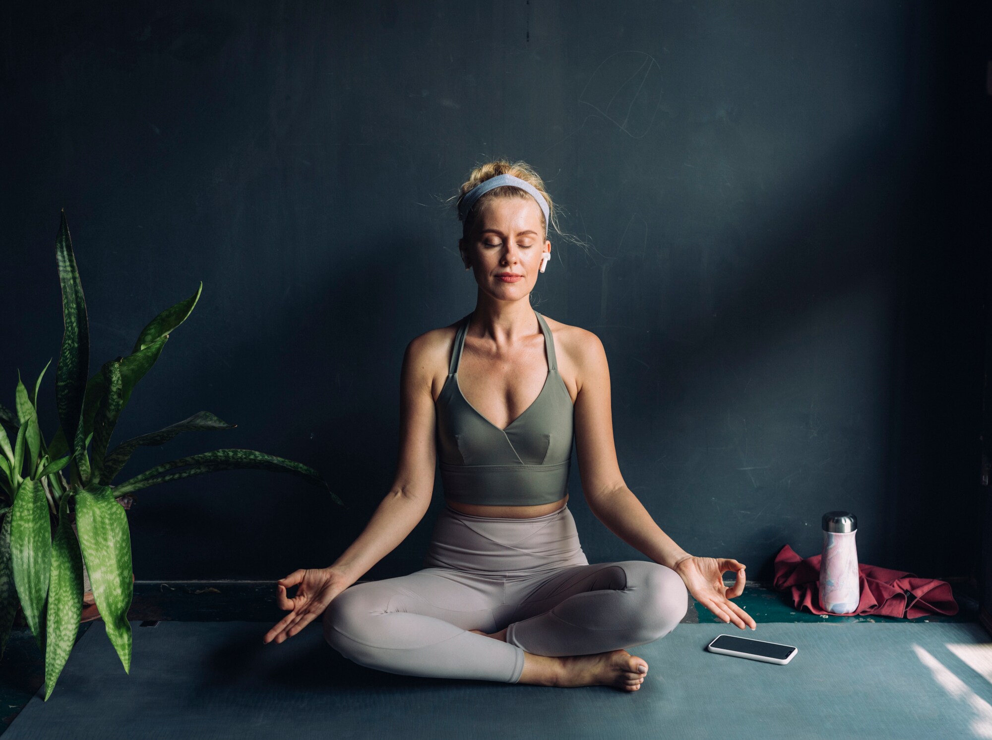 Eine Frau meditiert in Lotus-Position und trägt dabei Kopfhörer