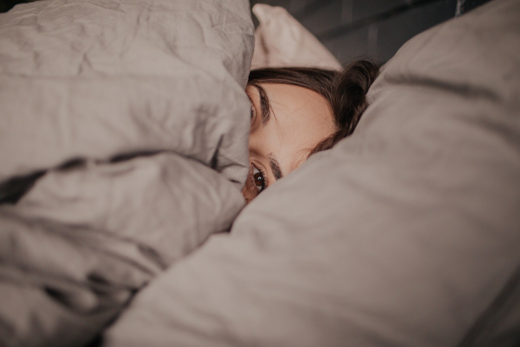Eine Frau liegt unter einer Bettdecke im Bett Eine Frau liegt unter einer Bettdecke im Bett
