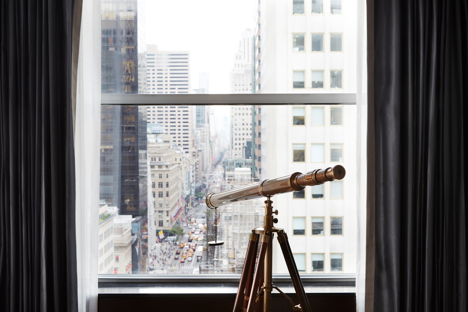 Blick durch ein Fenster auf die Fifth Avenue, am Fenster steht ein Fernrohr