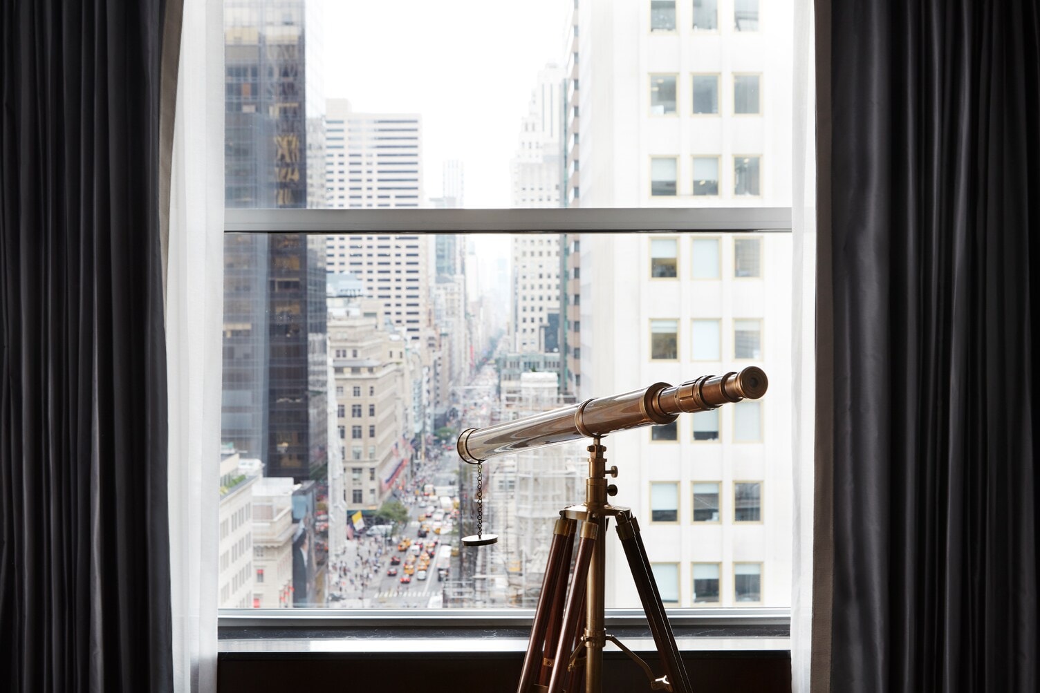 Blick durch ein Fenster auf die Fifth Avenue, am Fenster steht ein Fernrohr Blick durch ein Fenster auf die Fifth Avenue, am Fenster steht ein Fernrohr