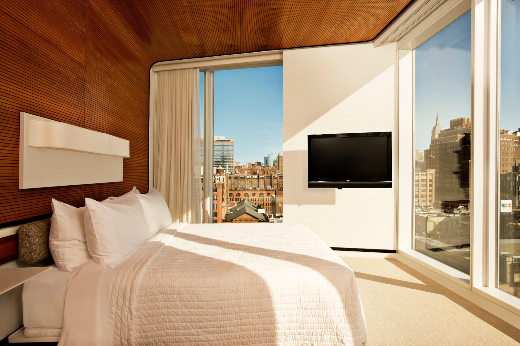 Ein Hotelzimmer mit großen Fenstern, durch die Hochhäuser zu sehen sind