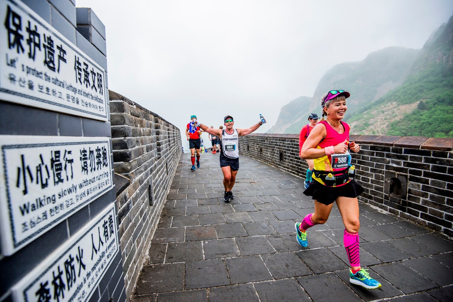 Jogger und Joggerinnen laufen über einen asphaltierten Weg in China beim Great Wall Marathon 2019. Jogger und Joggerinnen laufen über einen asphaltierten Weg in China beim Great Wall Marathon 2019.